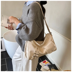 Détail du sac hobo crème avec boucles décoratives et poche latérale à rivets