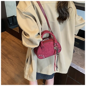 Detail of burgundy suede Boston bag featuring metallic studs and woven handle decor