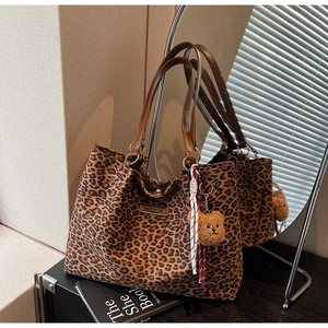 Dettaglio della borsa tote leopardata con logo in pelle e ciondolo a forma di orsetto