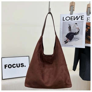 Detail of the soft dark brown suede hobo bag with wide shoulder strap in a minimalist style