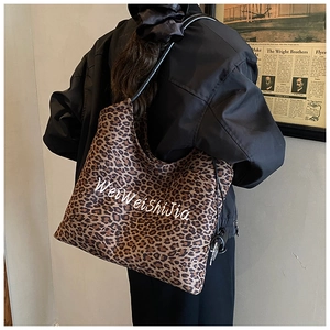 Leopard print tote bag with artistic white script on durable canvas worn by a model