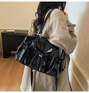 Détail d'un sac cabas plissé noir avec cuir brillant et boucle métallique argentée