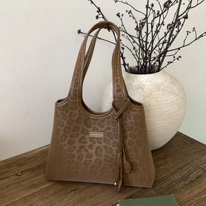 Detail view of leopard print tote bag with gold label on a rustic wooden table