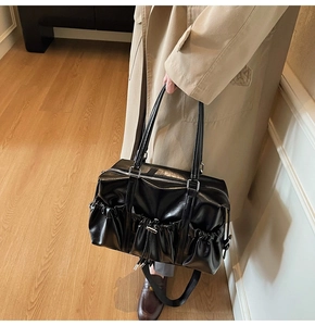 Détail d'un sac cabas noir brillant avec poches latérales à cordon et anses