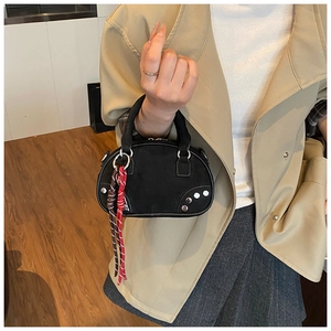 Détail d'un mini sac bowling noir avec clous argentés et charms tressés sur mannequin