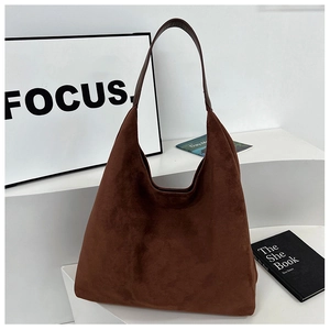 Detailed view of a dark brown suede tote bag on a minimalist white display