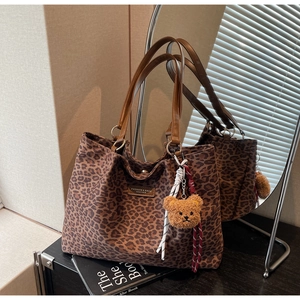 Dettaglio della borsa tote leopardata con patch in pelle marrone e ciondolo a orsetto