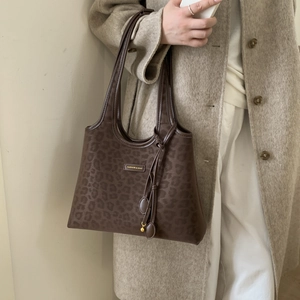 Detail of leopard print tote bag with gold metal plate and knotted shoulder strap