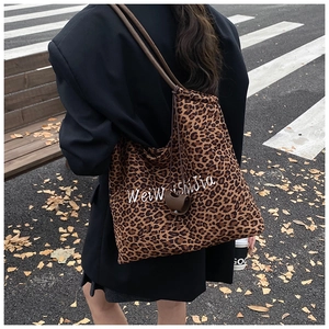Detail of leopard print tote bag featuring white letter embroidery and drawstring closure
