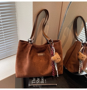 Detail of dark brown faux suede tote bag with leather strap and cute plush bear charm