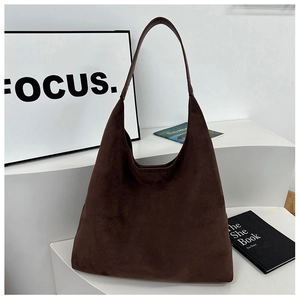 Detailed close-up of a minimalist dark brown suede hobo bag on a minimalist display stand