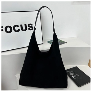 Close-up of black matte suede tote bag on white stairs showing its soft texture