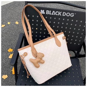 Close-up of cream checkerboard tote bag with brown leather tassels and a dog charm