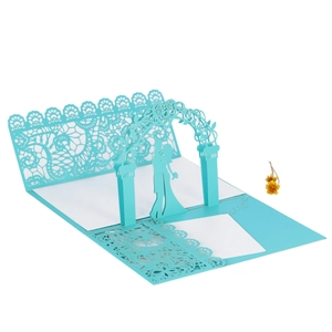 Detailed laser-cut wedding card featuring a 3D silhouette of a couple under a blue floral arch