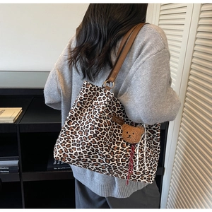 Dettaglio della borsa tote leopardata con cinturini in pelle marrone e ciondolo a orsetto