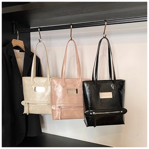 Trois sacs cabas élégants en beige, rose et noir suspendus sur un portant moderne