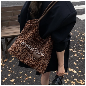 Detail of leopard print tote bag with white embroidery and dark brown handles