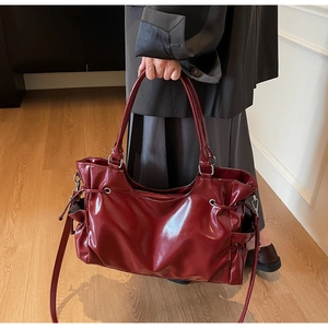 Détail du sac cabas en cuir verni bordeaux avec cordons de serrage et bandoulière réglable