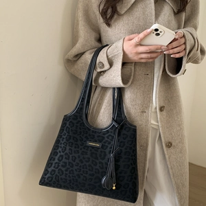 Close-up of black leopard print tote bag with gold metal logo and leather tassel detail