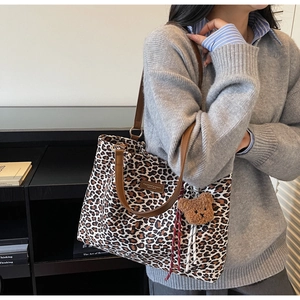 Dettaglio della borsa tote scamosciata leopardata con tracolla in pelle e ciondolo orsetto