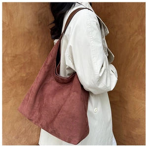 Side view of a vintage burgundy suede tote bag styled with a beige trench coat