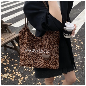 Street style shot of a leopard print canvas tote bag with embroidery on a city walk