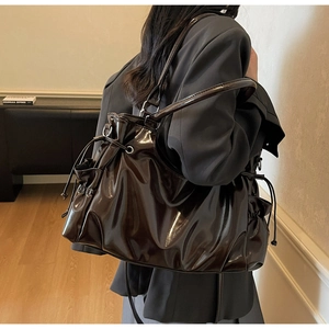 Détail du grand sac cabas en cuir verni marron avec texture plissée et cordon latéral