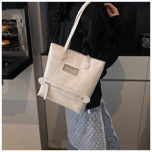 Détail du cabas blanc cassé en cuir ciré brillant avec fermeture éclair et boucle en métal