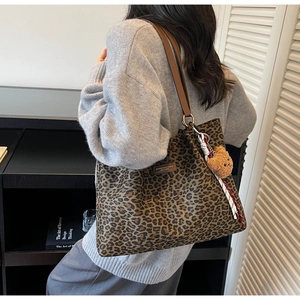 Dettaglio borsa tote scamosciata leopardata con tracolla in pelle e ciondolo a forma di orso