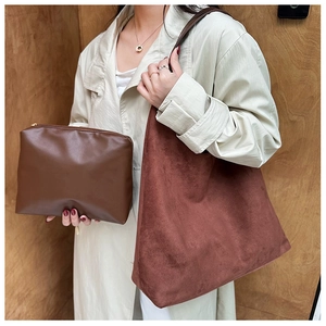 Detail of red-brown suede tote bag and brown leather clutch pouch on a model