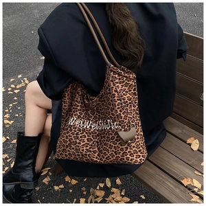 Detailed view of leopard print tote bag with brown straps worn by a model in autumn