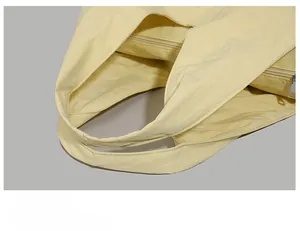 Detail of light yellow nylon tote bag featuring a silver zipper and wide handles