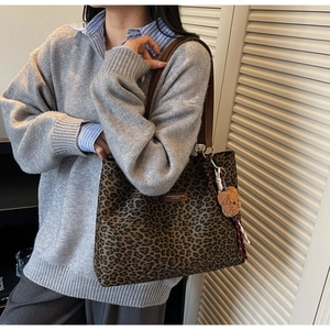 Dettaglio della borsa tote leopardata con cinturini in pelle marrone e ciondolo