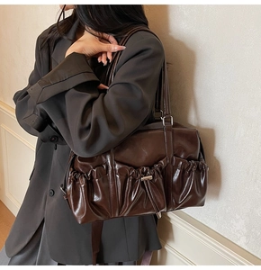 Détail d'un sac cabas en cuir marron foncé brillant avec poches plissées à l'avant
