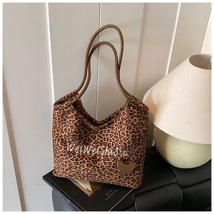 Close-up of leopard print canvas tote bag with embroidered lettering and leather handles