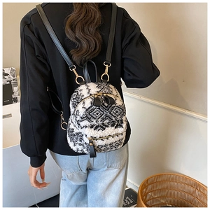 Detail eines Plüsch-Rucksacks mit schwarz-weißem Rautenmuster und goldenen Details