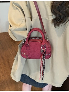 Retro burgundy suede handbag with metallic studs and striped strap shown on model