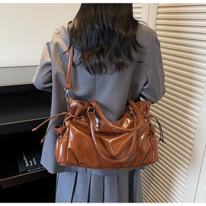 Brown patent leather tote with drawstring sides shown on model in a stylish office look