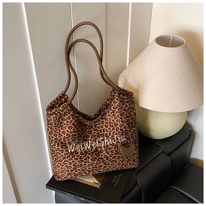 Close-up of leopard print tote bag with brown leather handles and heart charm accessory