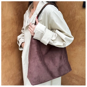 Detailed close-up of a large vintage tote bag in dark mauve suede with thin leather straps