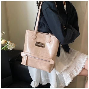 Détail d'un grand sac fourre-tout beige avec logo métallique et poche zippée avant