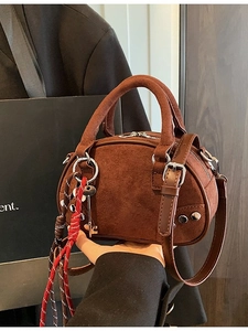 Brown suede Boston bag with silver studs and braided charms shown in a vintage setting