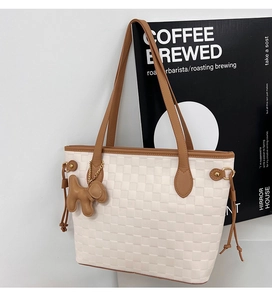 Detail of off-white checkered tote bag with brown leather straps and puppy charm