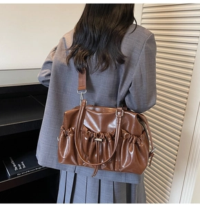 Detail of dark brown glossy tote bag with stylish pleats and wide shoulder strap