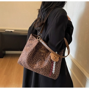 Dettaglio della borsa tote leopardata con manici marroni e ciondolo orsetto di peluche