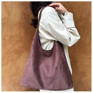 Detail of coffee suede tote bag with slim dark brown leather shoulder straps worn by model