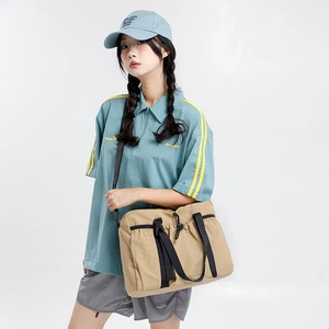 Detail of light brown nylon travel tote bag showing durable black straps and buckles