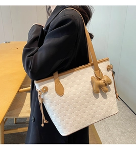 Detail of white woven tote bag with brown trim and cute dog pendant accessory