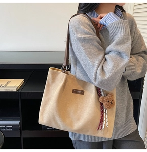 Detail of beige tote bag with leather straps and cute plush bear charm accessory