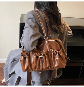 Détail du cabas en similicuir marron caramel avec plis latéraux et accents de cordon
